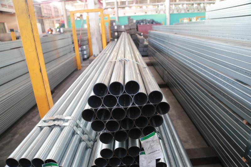 Hình ảnh một người công nhân đang kiểm tra chất lượng bề mặt hoặc kích thước của ống thép mạ kẽm